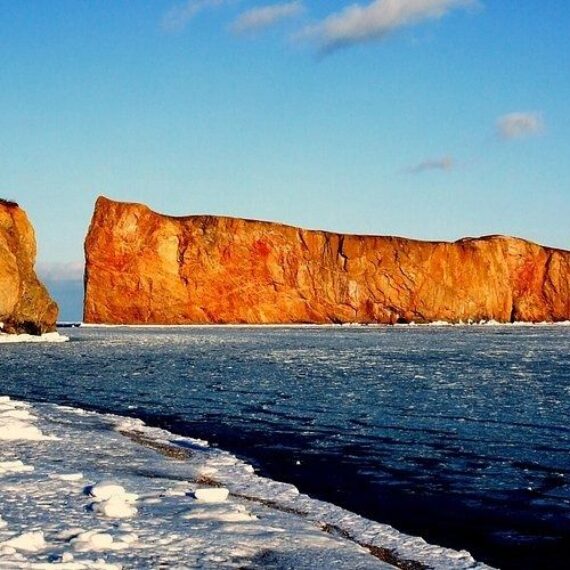 Rocher Percé et maison en bord de mer sous un ciel bleu