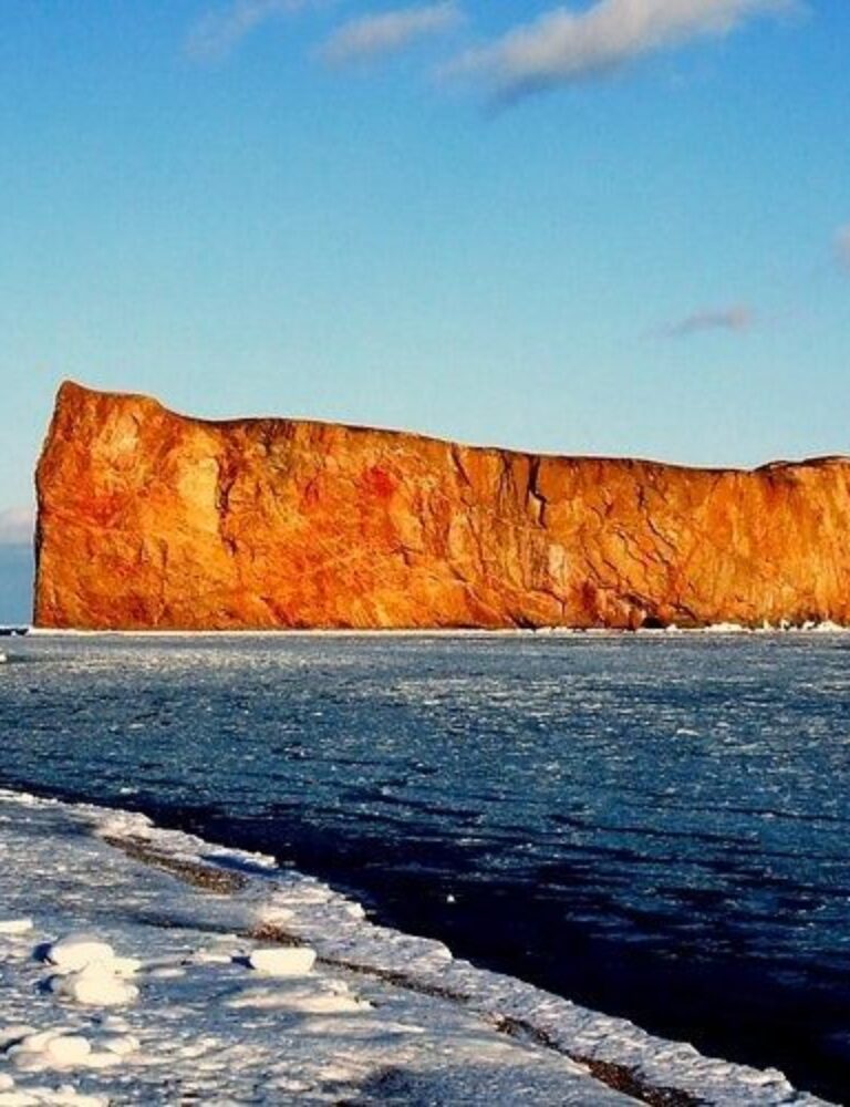 Rocher Percé et maison en bord de mer sous un ciel bleu
